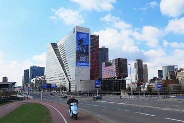 78 Een scooter op het fietspad richting de Willemsbrug. In het midden De Willemswerf met een grote reclame voor de ...